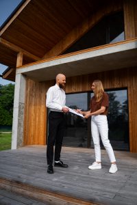2 personnes qui discutent devant la grande baie d'une maison en bois